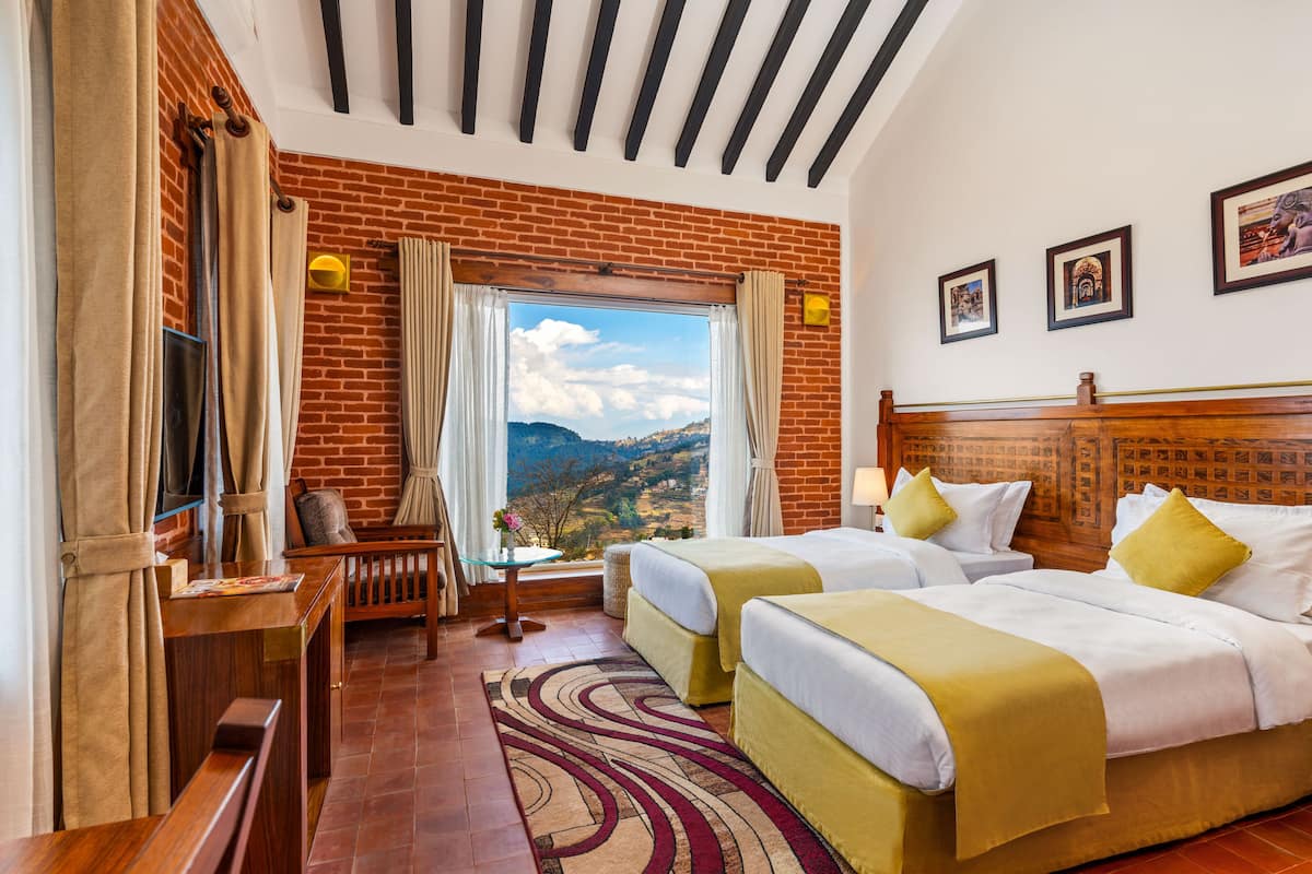 Une chambre d’hôtel avec deux lits, une tête de lit en bois, une vue sur les montagnes et un mur en briques.