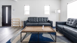 A modern living room with a dark leather sofa, a wooden coffee table, and a blue patterned rug. - NEWLY RENOVATED BUNGALOW WITH FREE PARKING ON SITE (Los Angeles)