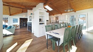 A spacious living area with a wooden ceiling, a dining table with chairs, and a kitchen area with white cabinets. - Spacious * Ocean View * Walking Trail to Beach * Hot Tub (Bodega Bay)