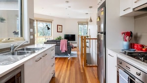 A modern kitchen with a built-in oven, a sink, and a dining area with a sofa. - Design/bright/cosy townhouse between airport &city (Glenroy)