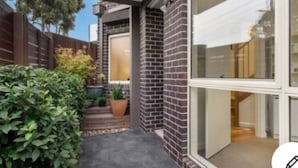 A modern house with a brick exterior, a covered porch, and a visible interior with a staircase. - Design/bright/cosy townhouse between airport &city (Glenroy)