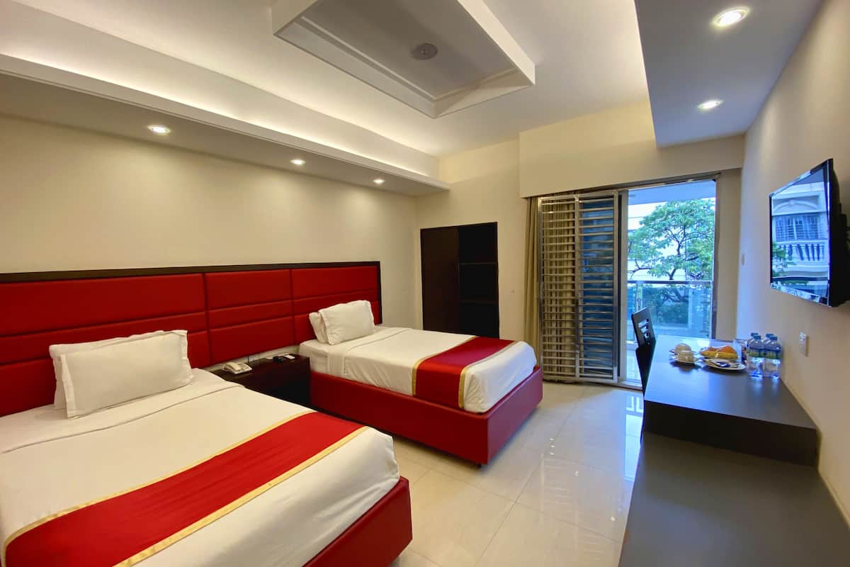 A hotel room with two beds, a desk, and a balcony with a view.