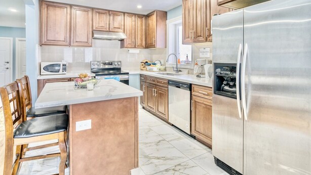 A modern kitchen with wooden cabinets, stainless steel appliances, and a marble floor. - Renovated Rooms 10-min to Finch Subway Near Yonge St (Toronto)