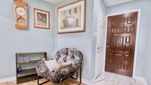 A room with a patterned armchair, a wooden door, and a wall clock. - Renovated Rooms 10-min to Finch Subway Near Yonge St (Toronto)