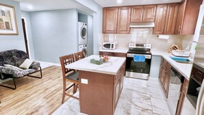 A modern kitchen with wooden cabinets, a central island, a built-in oven, and a microwave. - Renovated Rooms 10-min to Finch Subway Near Yonge St (Toronto)