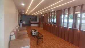 A hotel lobby with a long reception desk, a seating area with sofas, a coffee table, and a large window with a view of the outside. - Hotel Prime Classic (Hyderabad)