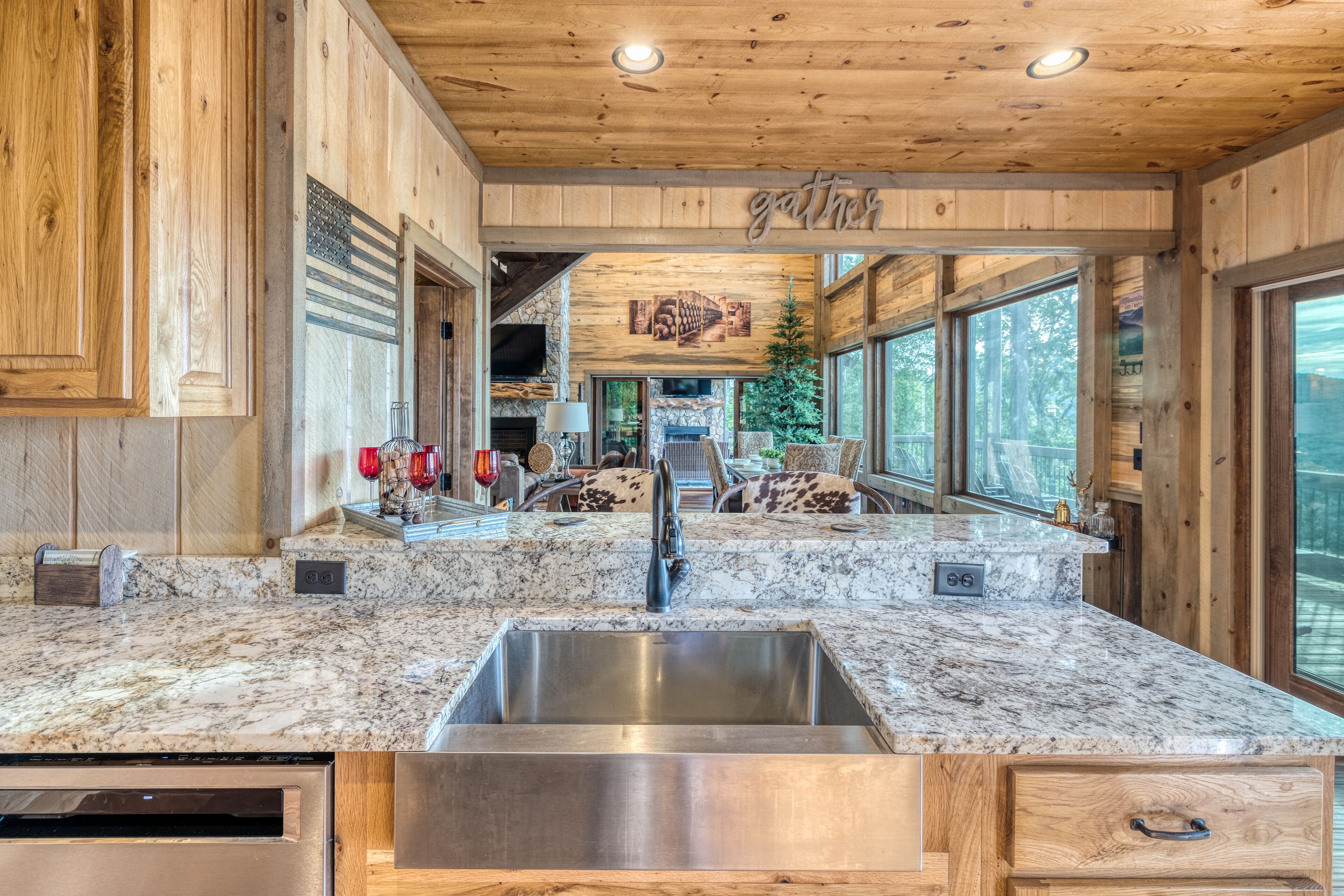 A kitchen with a granite countertop, stainless steel sink, wooden cabinets, and a stone fireplace.