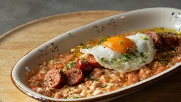 A dish with sausage, egg, and herbs on a wooden board.