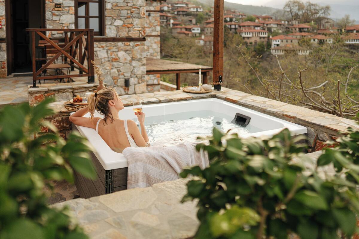 Una persona relajándose en un jacuzzi con vistas a un pueblo.