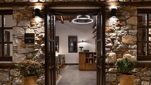 Uma área de recepção com paredes de pedra, vigas de madeira e um lustre moderno.