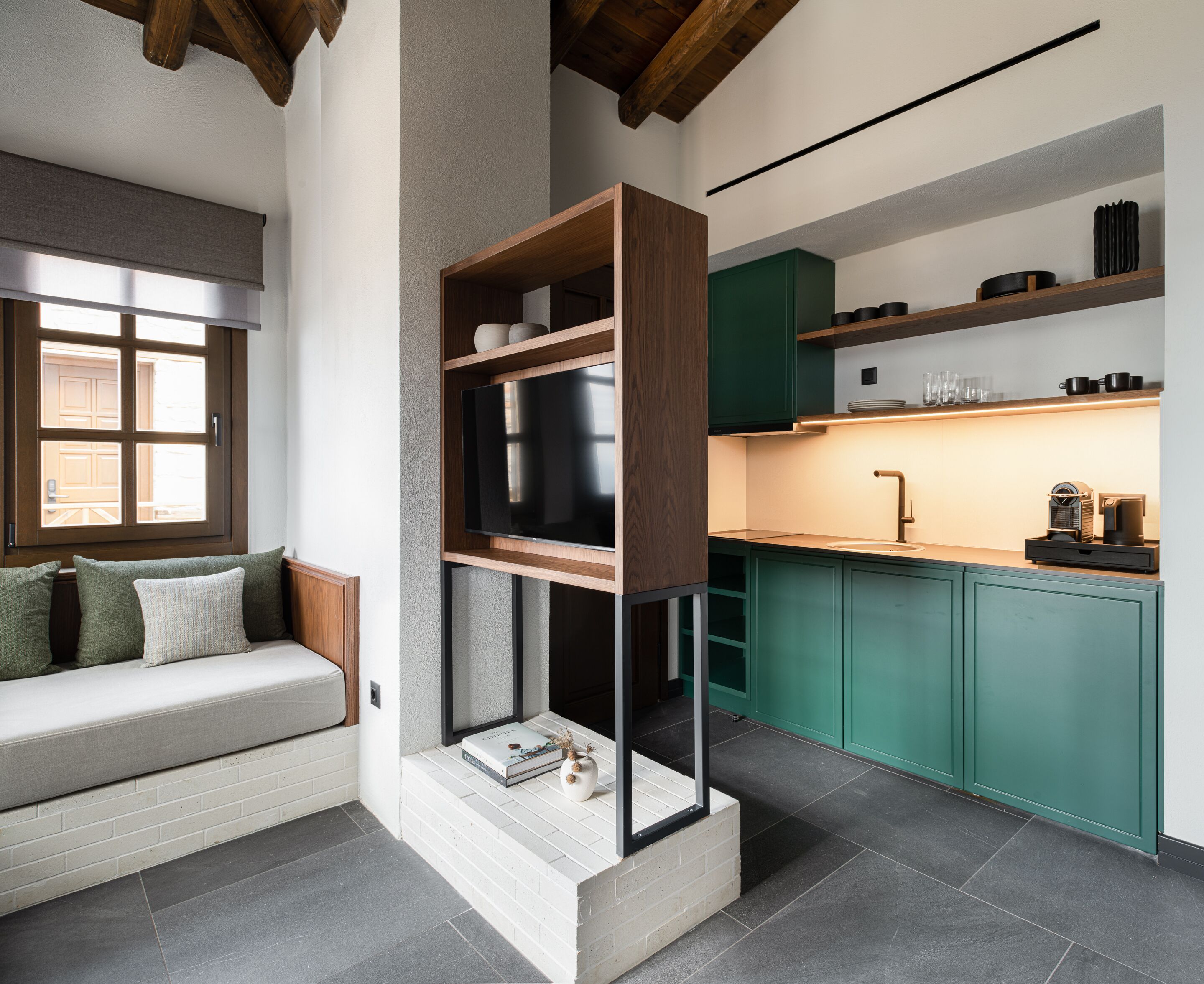 A modern kitchen with green cabinets, a built-in oven, and a countertop with a coffee machine.
