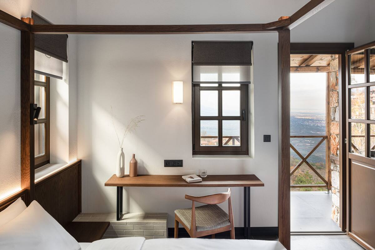 Un dormitorio con techo de madera, un escritorio con silla, una ventana y vistas al exterior.