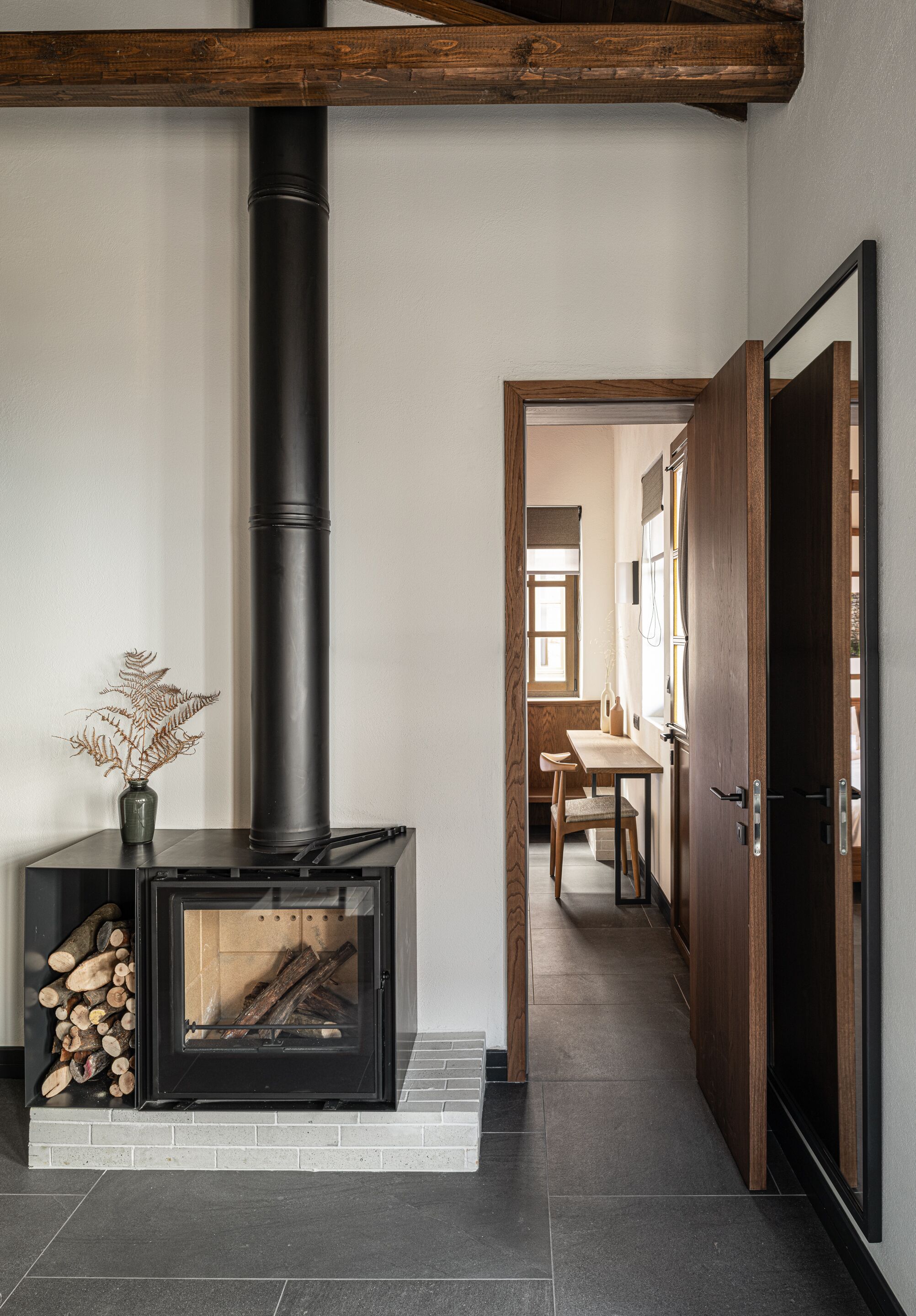Een moderne keuken met een ingebouwde houtkachel, een eethoek met een tafel en stoelen, en een houten deur.