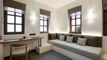 A modern room with a built-in bench, a desk, and two windows with blinds.