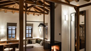 Um quarto acolhedor com lareira, vigas de madeira, um sofá e uma mesa.