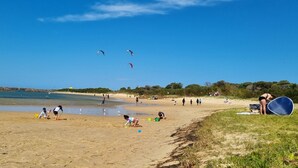 A beach with people playing and flying kites. - Sunset Lakeview. (Windang)