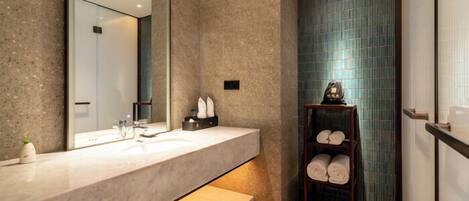 A modern bathroom with a large mirror, a marble sink, and a towel rack.
