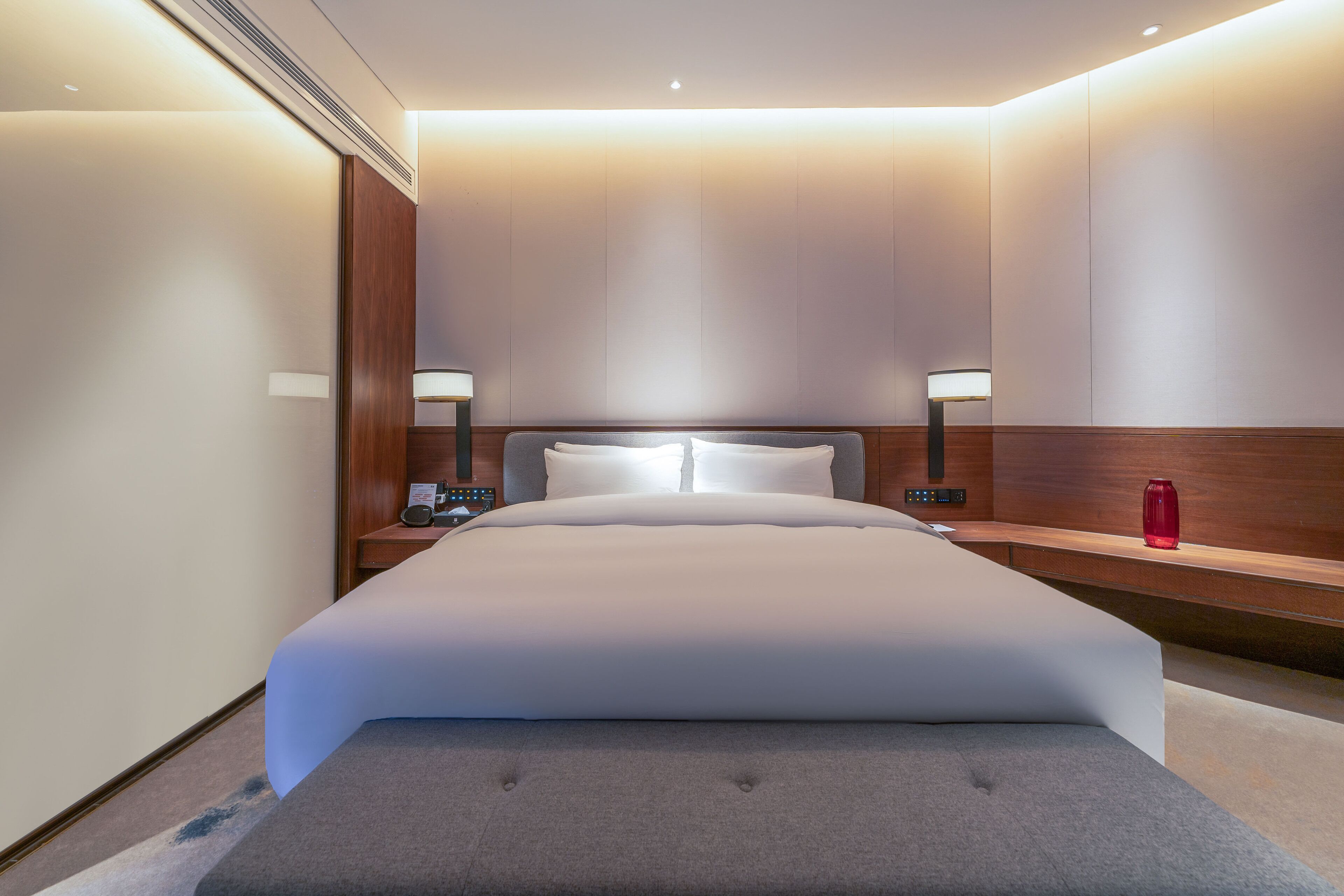 Una habitación de hotel moderna con una cama grande, mesitas de noche y un buró.