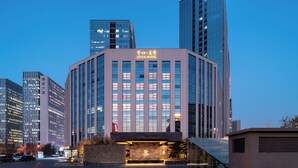 Un edificio de hotel moderno con una entrada destacada y varios pisos.