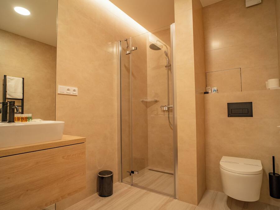 Une salle de bain moderne avec une douche à parois de verre, un lavabo blanc et des toilettes.