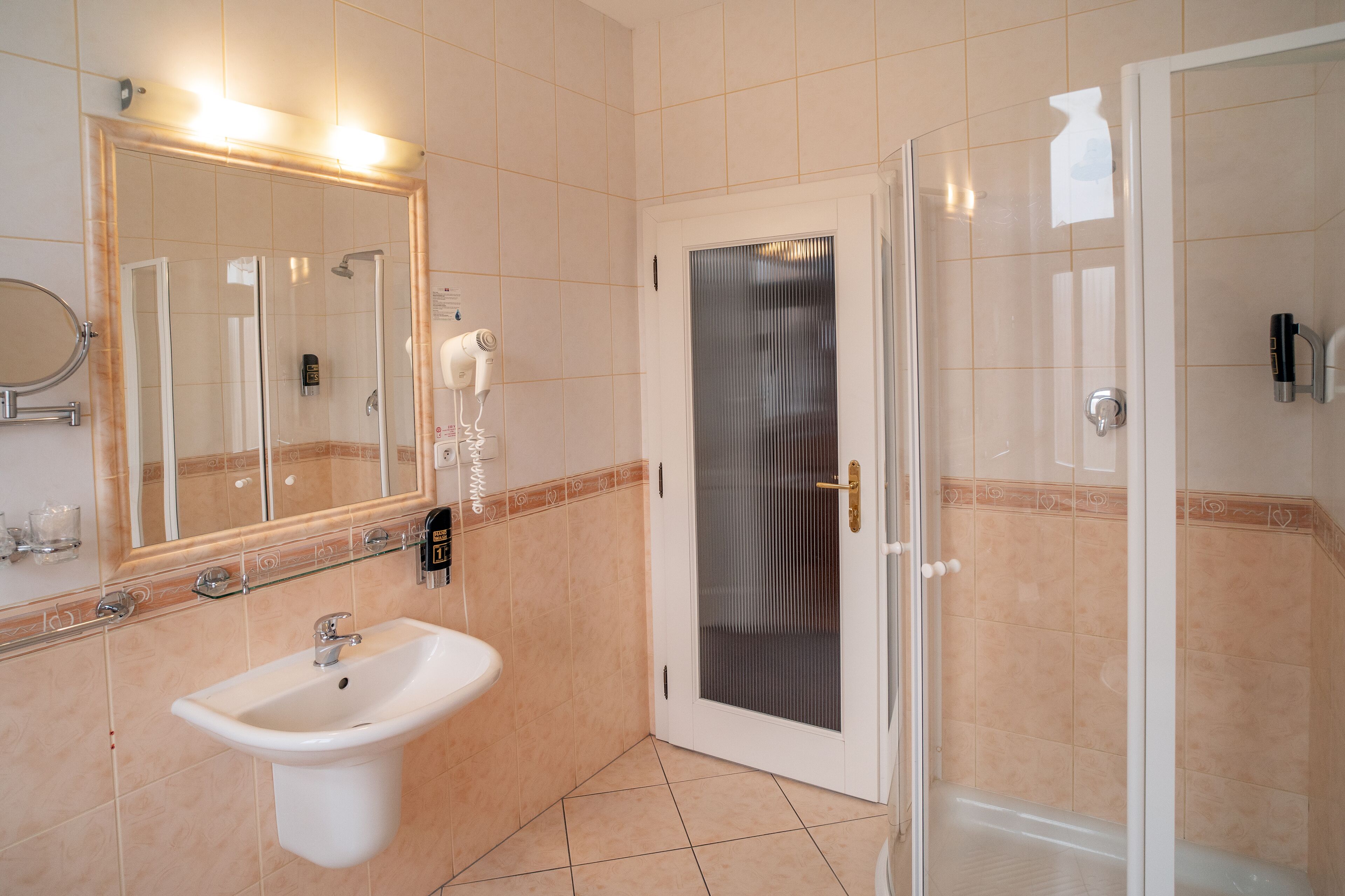 Une salle de bain équipée d’un lavabo, d’un miroir et d’un espace douche.