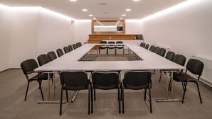A conference room with a long table and chairs, a wooden panel, and a mirror on the wall. - Hotel U Kaplicky (Pisek)