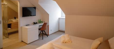 A modern bedroom with a bed, a desk, and a TV.