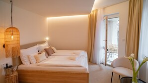 A modern hotel room with a large bed, a small table with a vase of flowers, and a chair. - Hotel U Kaplicky (Pisek)