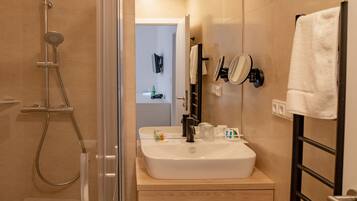 Un baño moderno con ducha de vidrio, lavamanos con espejo y barra para toallas.