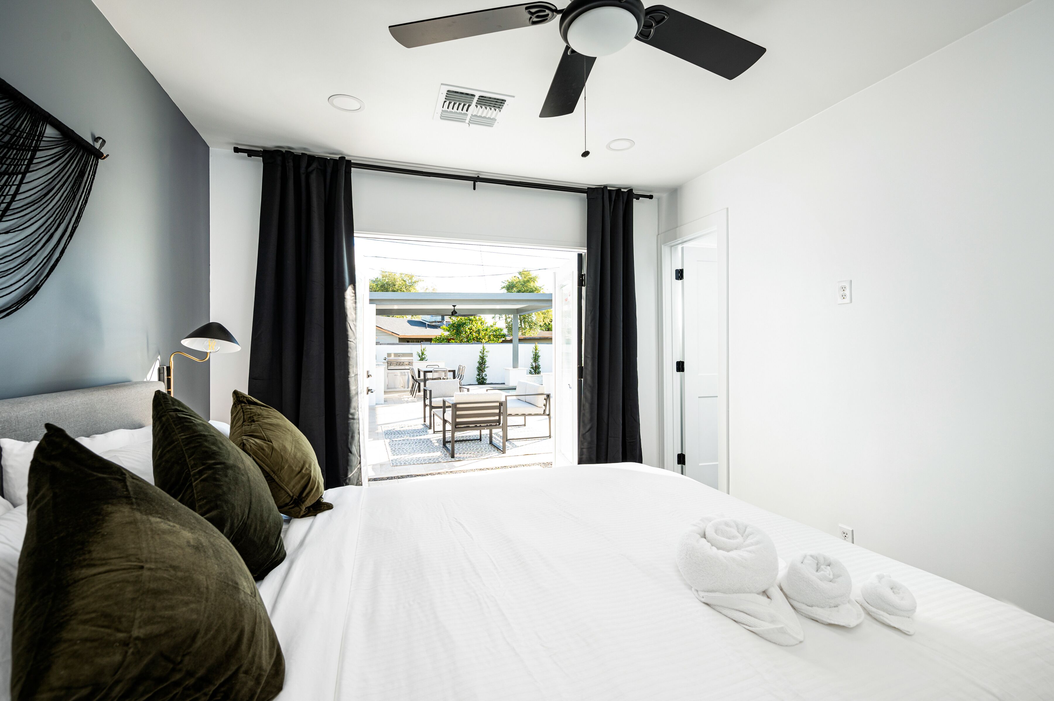 Et hotelværelse med en seng, puder, en ventilator i loftet og udsigt til udeområdet.