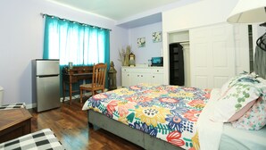 Une chambre à coucher comprenant un lit, un bureau, une chaise, une armoire et un réfrigérateur.