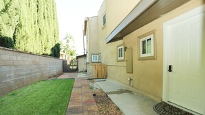 Un immeuble résidentiel avec une allée pavée, une petite pelouse et une clôture en bois.