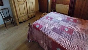 Une pièce en bois avec un lit, une armoire, une chaise et une fenêtre avec des rideaux.