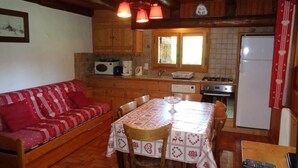 Une cuisine chaleureuse avec une table en bois, des chaises et un canapé rouge.