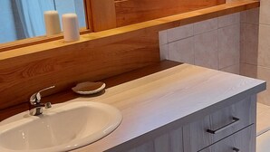 Une salle de bain moderne avec un meuble-lavabo en bois, un grand miroir et une fenêtre.