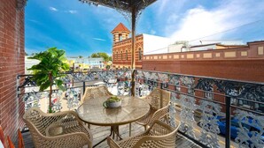 A balcony with wicker furniture and a view of a building with a tower.