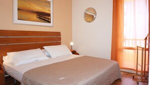 Une chambre d’hôtel avec un grand lit, une table de chevet, un miroir fixé au mur et une fenêtre avec des rideaux.