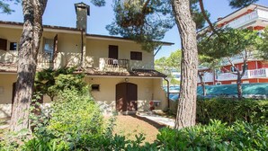 Un bâtiment à deux étages doté d’un balcon, entouré d’arbres et de verdure.