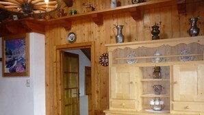 Une cuisine en bois avec un meuble en bois, une horloge et une porte donnant sur une autre pièce.