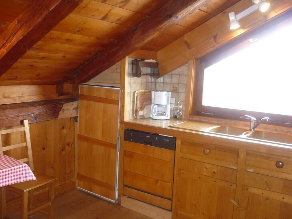Eine Küche mit Holzmöbeln, inklusive Kühlschrank, Geschirrspüler und Kaffeemaschine.