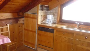 Une cuisine en bois équipée d’un réfrigérateur, d’un lave-vaisselle et d’une machine à café.