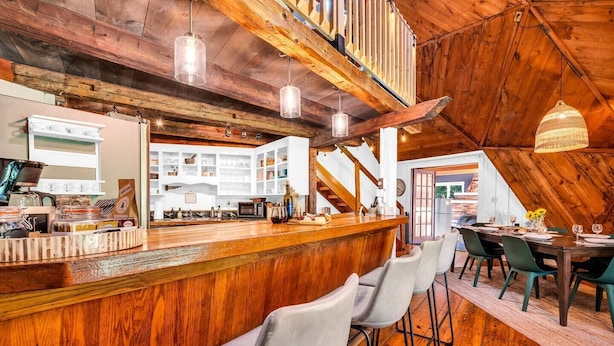 A rustic interior with a wooden bar, seating area, and a staircase leading to an upper level. - Unique Dome with HotTub & Mtn Views (Bryant Pond)
