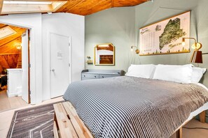 Ein Schlafzimmer mit einem großen Bett, einer Holzbalkendecke, einer Karte an der Wand und einem kleinen Schreibtisch.