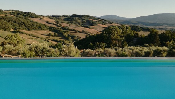 A pool with a view of rolling hills and mountains in the background. - Tuscan country house with enchanting view and swimming pool (Radicondoli)