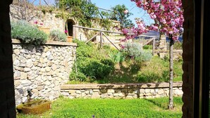 A stone wall with a small water feature, a grassy area, and flowering trees. - Tuscan country house with enchanting view and swimming pool (Radicondoli)