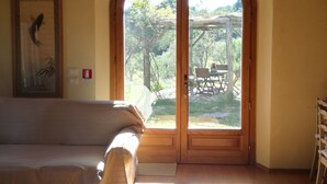 A room with a wooden ceiling, a large arched door leading outside, a framed picture on the wall, and a bed with pillows. - Tuscan country house with enchanting view and swimming pool (Radicondoli)