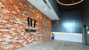 A lobby with a brick wall, a reception desk, and a modern ceiling design. - 1 Bedroom Adelaide CBD Centre Apartment (Adelaide)