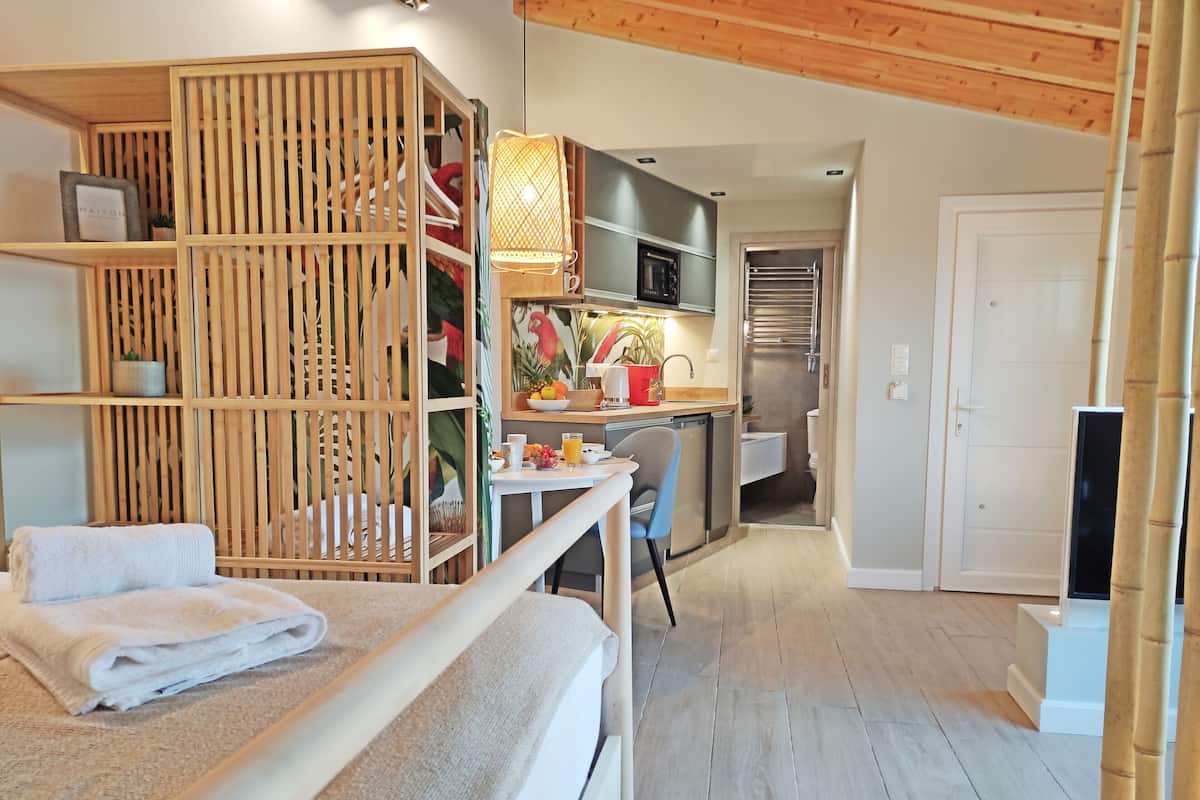 Una habitación de hotel pequeña con una cama, una kitchenette, un baño y un separador de madera.