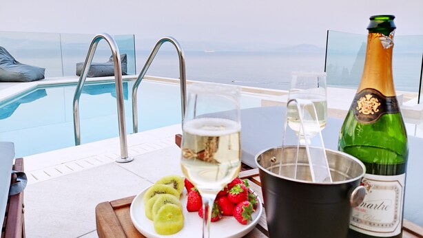 Ein Poolbereich mit einer Champagnerflasche, einem Glas Weißwein und Obst auf einem Tablett.