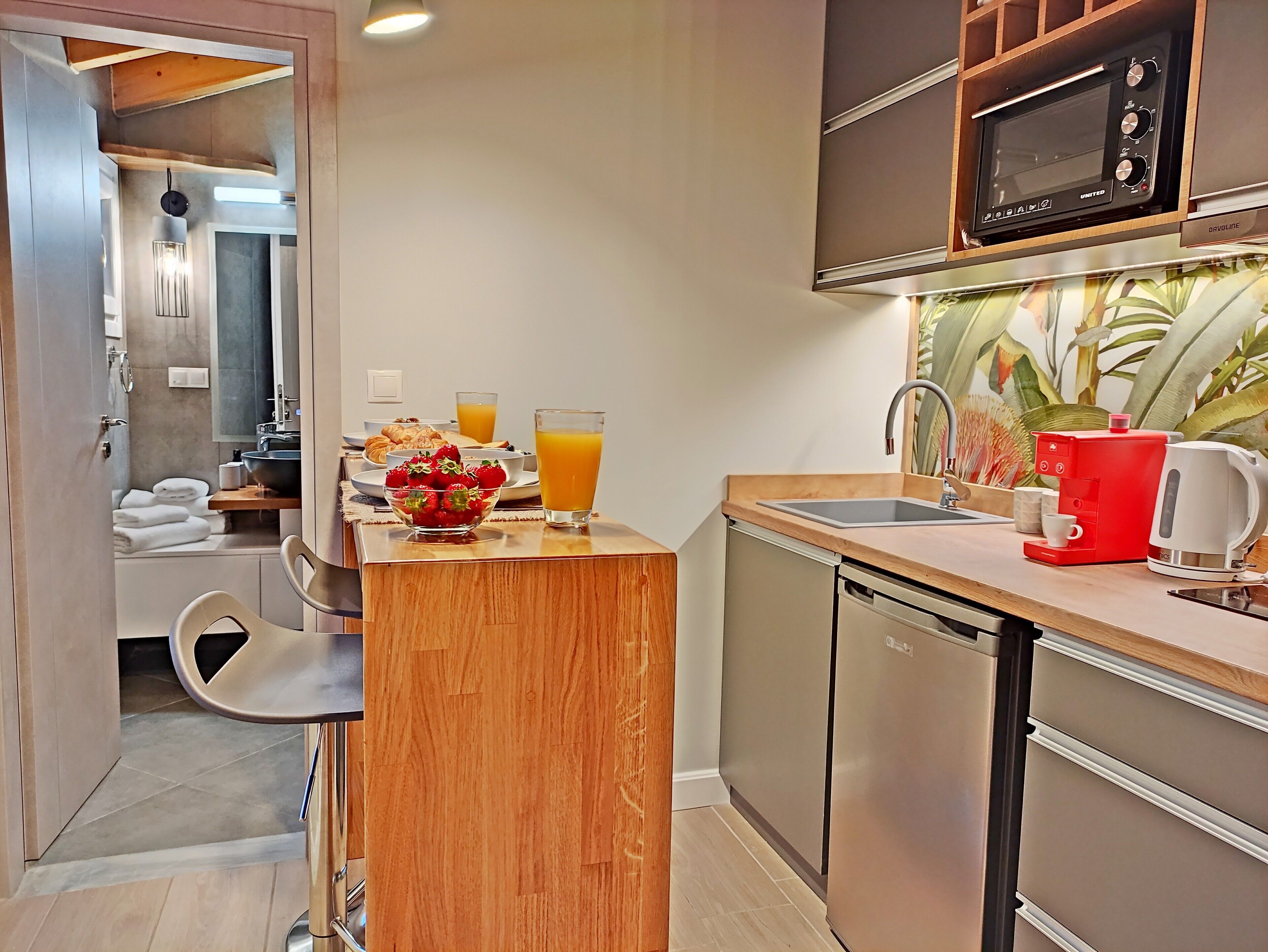 A modern kitchen with a wooden bar counter, a microwave, a coffee maker, and a sink.